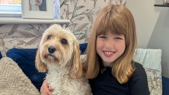 A young girl smiles while cuddling a dog.