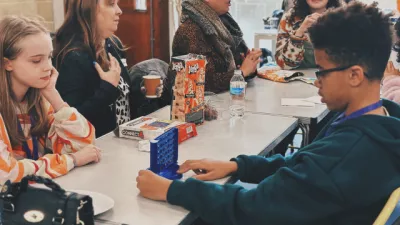 Young people play games and eat snacks at a table at a Youth Support Meeting.
