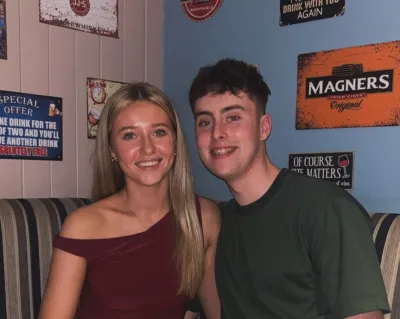 A woman and her friend smile in a corner seat in a bar.