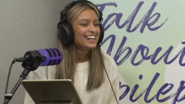 A young girl with headphones laughing on recording of podcast