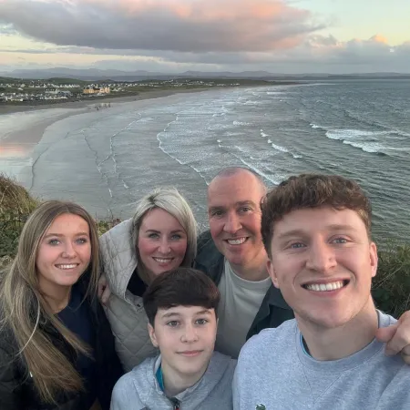 A family smiles for a photo on a beach.