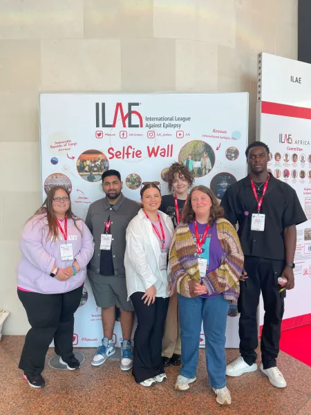 Young Epilepsy representatives stand in front of the International League Against Epilepsy selfie wall.