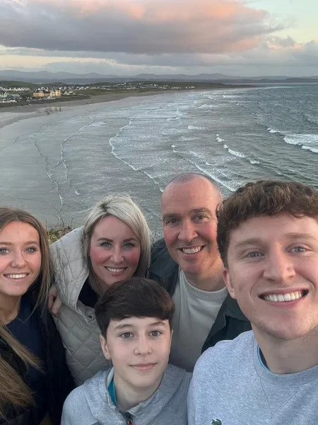 A family smiles for a photo on a beach.