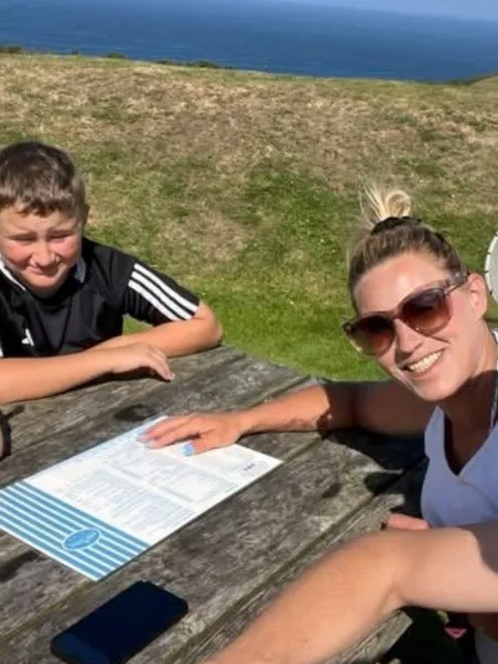 A family sits at a bench by the ocean.